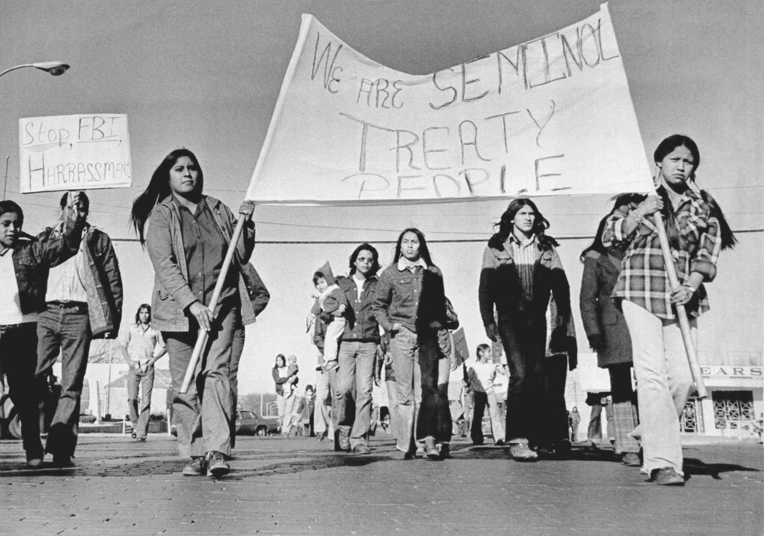 Native people holding a banner that reads "we are Seminole treaty people" during a protest.