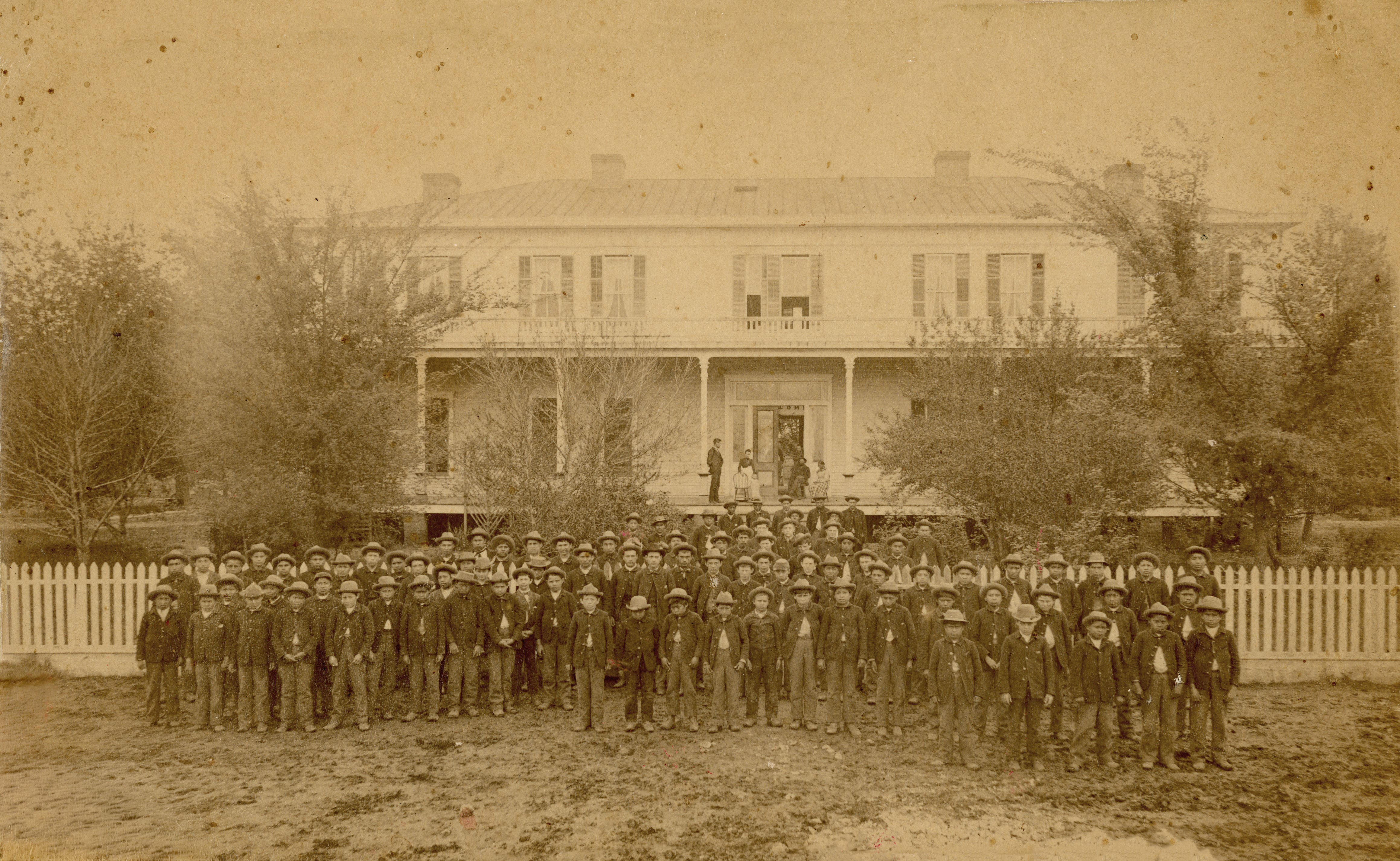 Historic photograph of youth standing in front of a building.