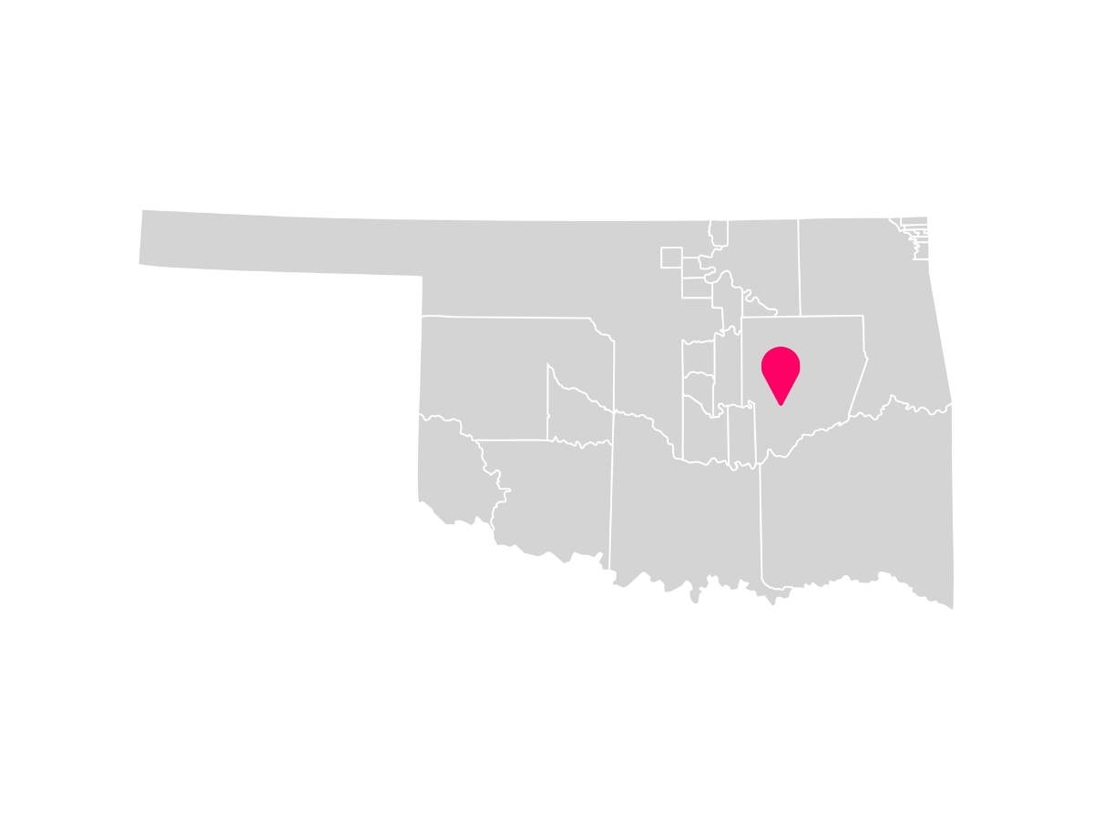 A gray map of Oklahoma's Tribal Jurisdictions with Okemah, Oklahoma marked with a pink pin where the Thlopthlocco Tribal Town's Headquarters is located inside the Muscogee (Creek) Nation.