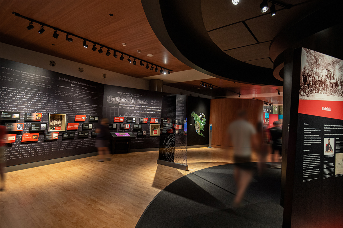 Inside of the "Upheaval" section of the OKLA HOMMA exhibit at First Americans Museum showing the timeline of Indian Removal on a black wall with government documents in white as the backdrop.