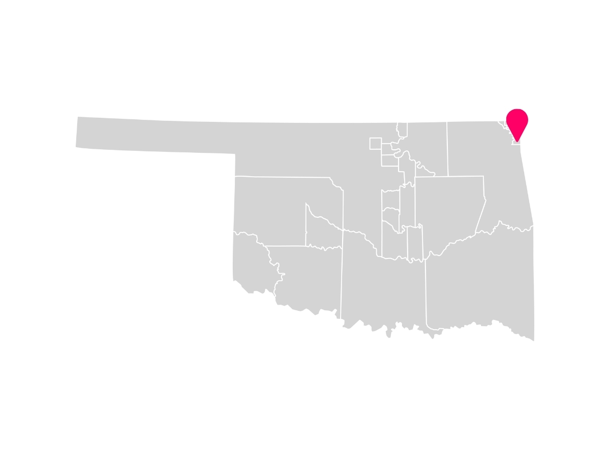 A gray map showing the tribal jurisdiction areas of Oklahoma with a pink pin marking Grove, Oklahoma, where the Seneca-Cayuga Nation is headquartered.