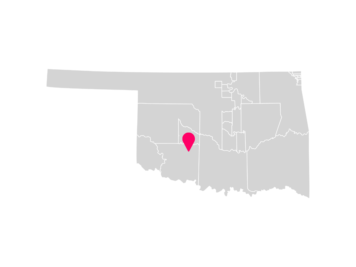 A gray map showing the tribal jurisdiction areas of Oklahoma with a pink pin marking Apache, Oklahoma, where the Fort Sill-Chiricahua-Warm Springs-Apache Tribe is headquartered.